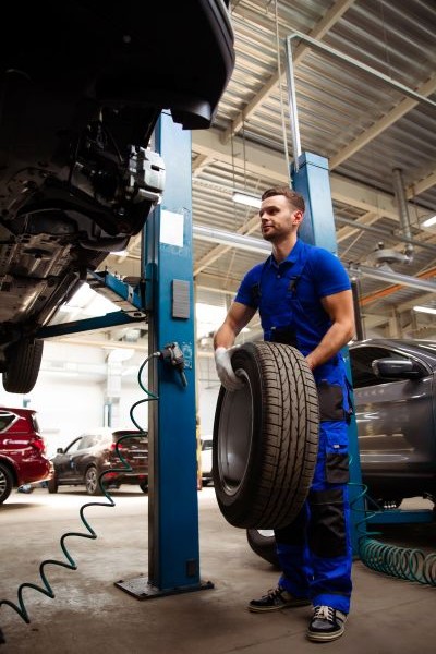 Mechanic underneath vehicle, holding wheel