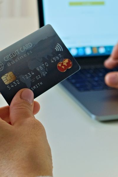 person holding credit card in front of laptop