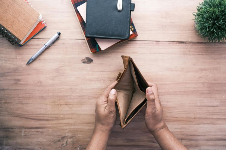 Person holding open an empty wallet on a desk