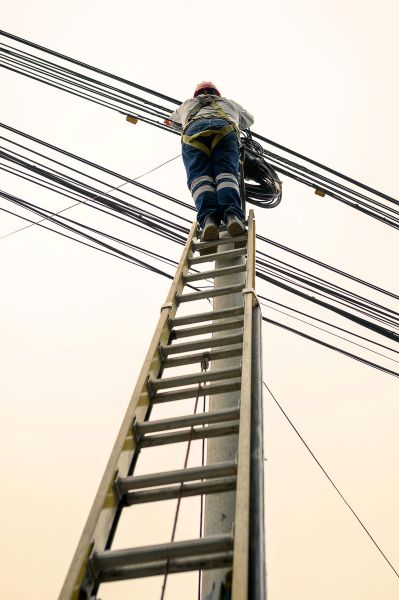 Man on ladder servicing some electricity cables